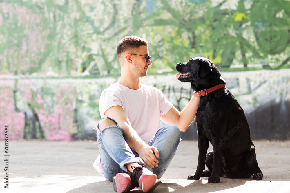 Guy in sunglasses hugs his dog in autumn park