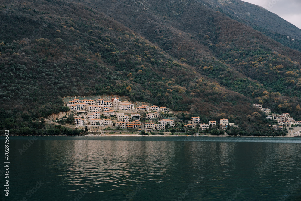 Residential buildings in Kostanjica at the foot of the green mountains. Kotor Bay, Montenegro