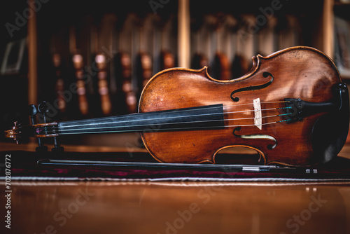 handmade viola leaning sideways with a row of violins on the background at a musical instrument store