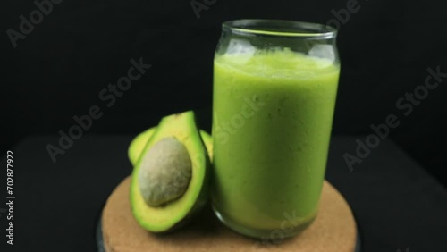 Rotating display of avocado juice on black background. photo