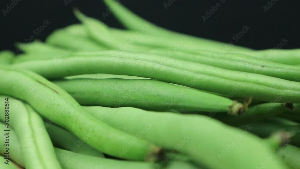 close up of green beans on rotating display, black background. close up of green beans on rotating display, black background.