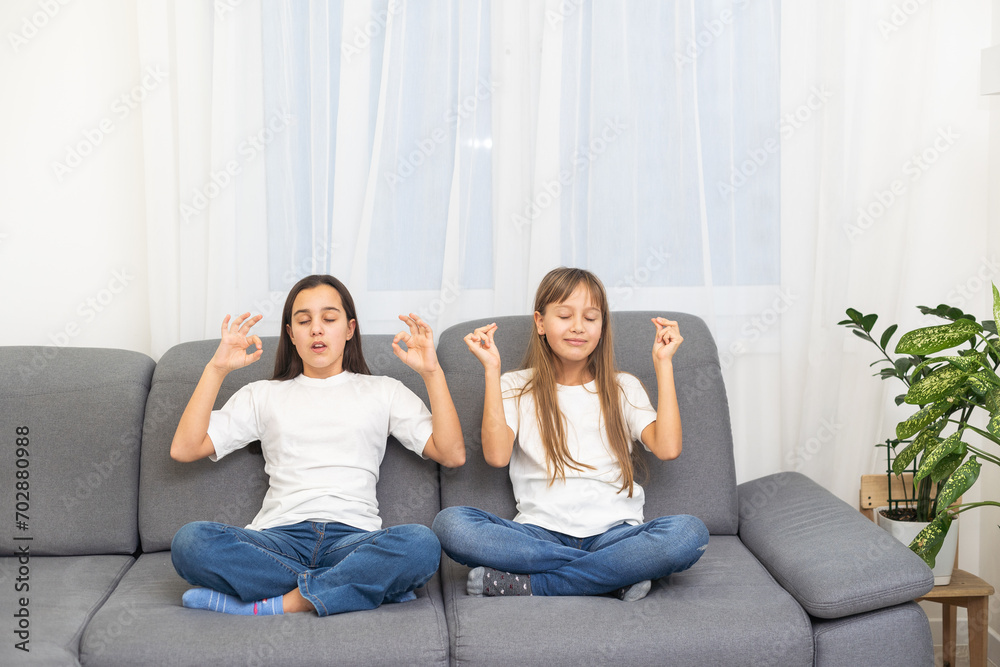 People, relationships, family, relaxation, yoga and meditation concept. girls sitting on bed, looking up, making mudra gesture, praying or meditating