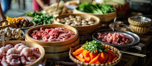Ingredients for steam boat hot pot in Asian halal buffet menu include a variety of cold and mixed raw meats, seafood, vegetables, mushrooms, satay, beancurd, and hot dogs on a stick in a basket.
