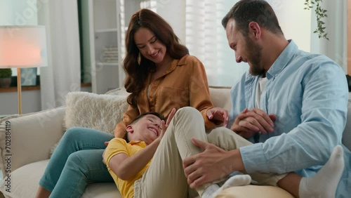 Loving playful parents mother father tickling son kid boy child mum dad tickle playing together sincere laughing enjoying having fun at home couch Bonding Caucasian family happy childhood parenthood photo