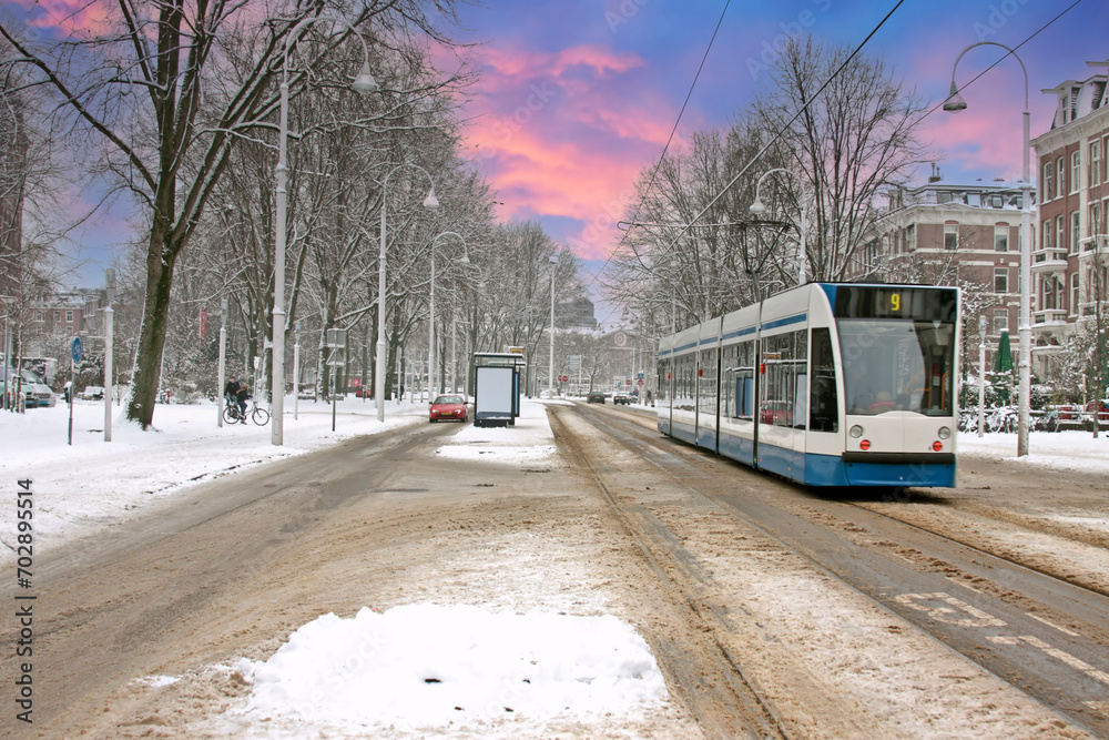 Obraz premium Tram driving in snowy Amsterdam in the Netherlands at sunset