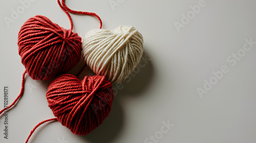 Red and white clews in the shape of a heart made from yarn on a white background, copy space for text