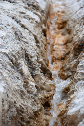 Small stream flows between brown ferruginous limestone rocks. Motion blur. Narrow depth of field. Background image photo