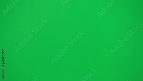 Portrait of thief on chroma key green screen background. Man robber in black balaclava and hoodie walking and looks around. photo