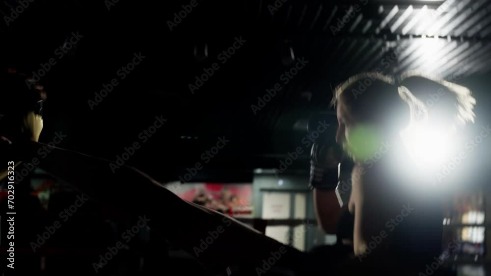 Sporty girl doing kicks in a boxing ring. Slow motion, low key. Sporty girl doing kicks in a boxing ring. Slow motion, low key.