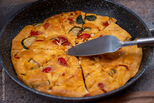 Close up of a vegetable frittata in a pan from the oven. The frittata is an Italian egg dish in which vegetables are fried in a pan with beaten eggs and other ingredients such as cheese and ham
