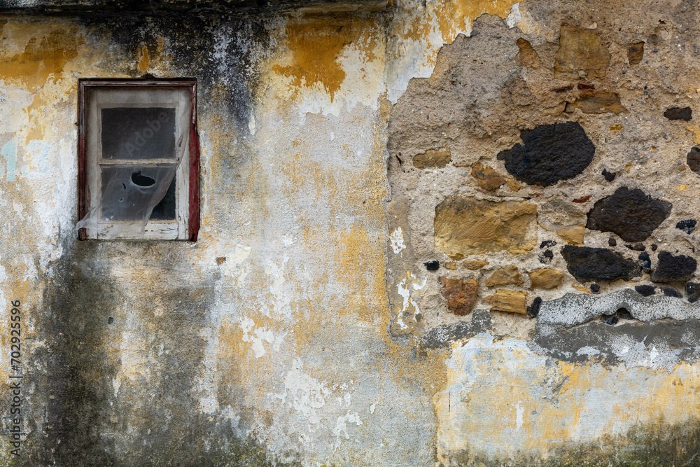 Lisbon, Portugal. 6 December 2023. Ancient building closeup of surface brick wall concrete plaster of an abandoned house with broken windows black stone grey cement and ocher and white paster.