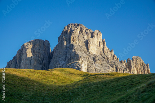 Sun shines on mountain in the dolomites: Grohmannspitze in Langkofelgruppe in the morning with clear blue sky in the background, South Tyrol, Italy