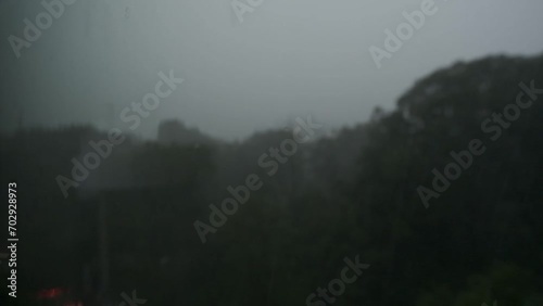 Closeup of rain falling against a window during a heavy rainstorm (ID: 702928973)