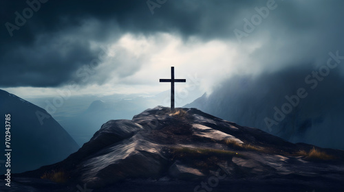 Wooden cross silhouette on rocky mountain top or peak, dark clouds on the sky. Christian faith or religion, crucifixion of Jesus Christ, Calvary sacrifice for salvation and forgiveness