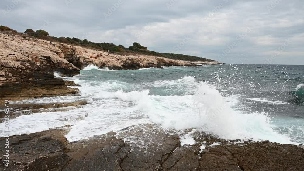 Waves crashing into rocks on the sea. Waves breaking on the shore. High cliffs by the sea. Rocky coastline. Waves crashing into rocks on the sea. Waves breaking on the shore. High cliffs by the sea. Rocky coastline.