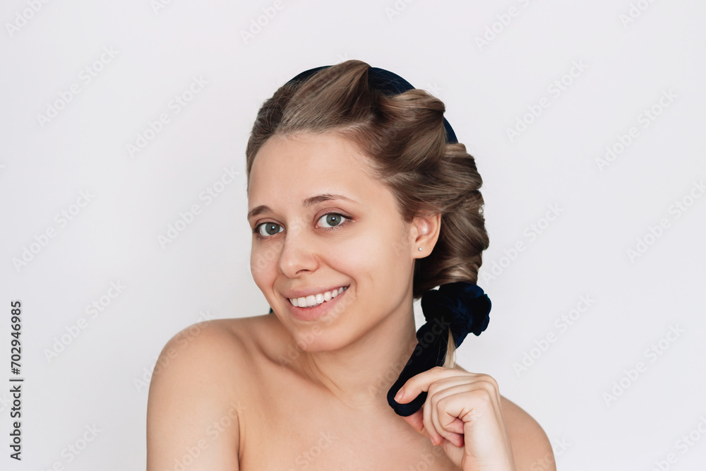 Heatless curl. A young attractive caucasian smiling blonde woman using soft curler to curl her hair without harm isolated on a white background. Healthy hair styling, no heating, no damage Heatless curl. A young attractive caucasian smiling blonde woman using soft curler to curl her hair without harm isolated on a white background. Healthy hair styling, no heating, no damage