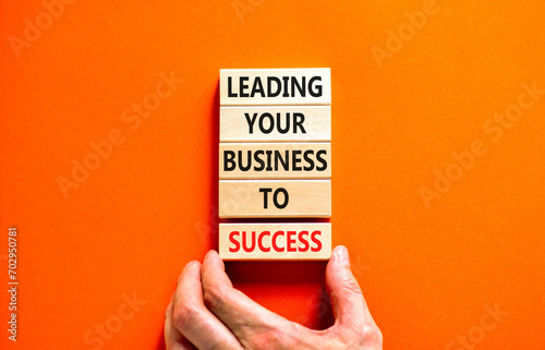 Leading your business to success symbol. Concept words Leading your business to success on wooden blocks. Beautiful orange table orange background. Leading your business to success concept. Copy space