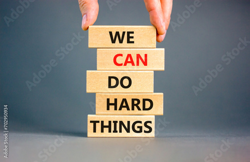 We can do hard things symbol. Concept words We can do hard things on wooden blocks. Beautiful grey table grey background. Businessman hand. Business, we can do hard things concept. Copy space. photo