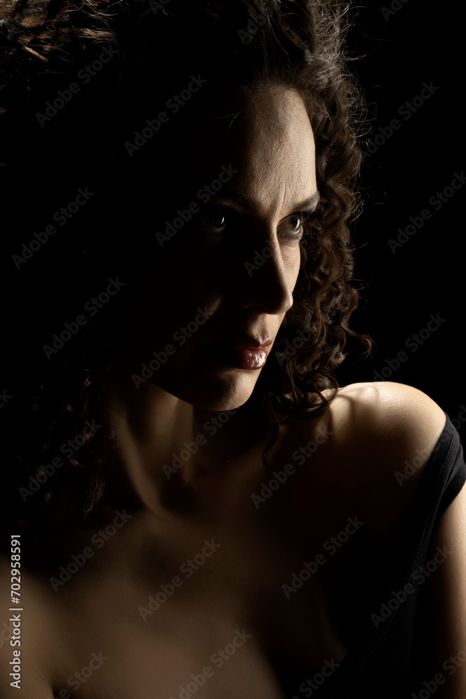 Sensual portrait of beautiful curly serious curly woman a black background