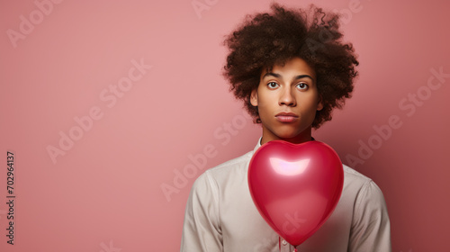 Man holding heart shaped balloon against pink background © MP Studio