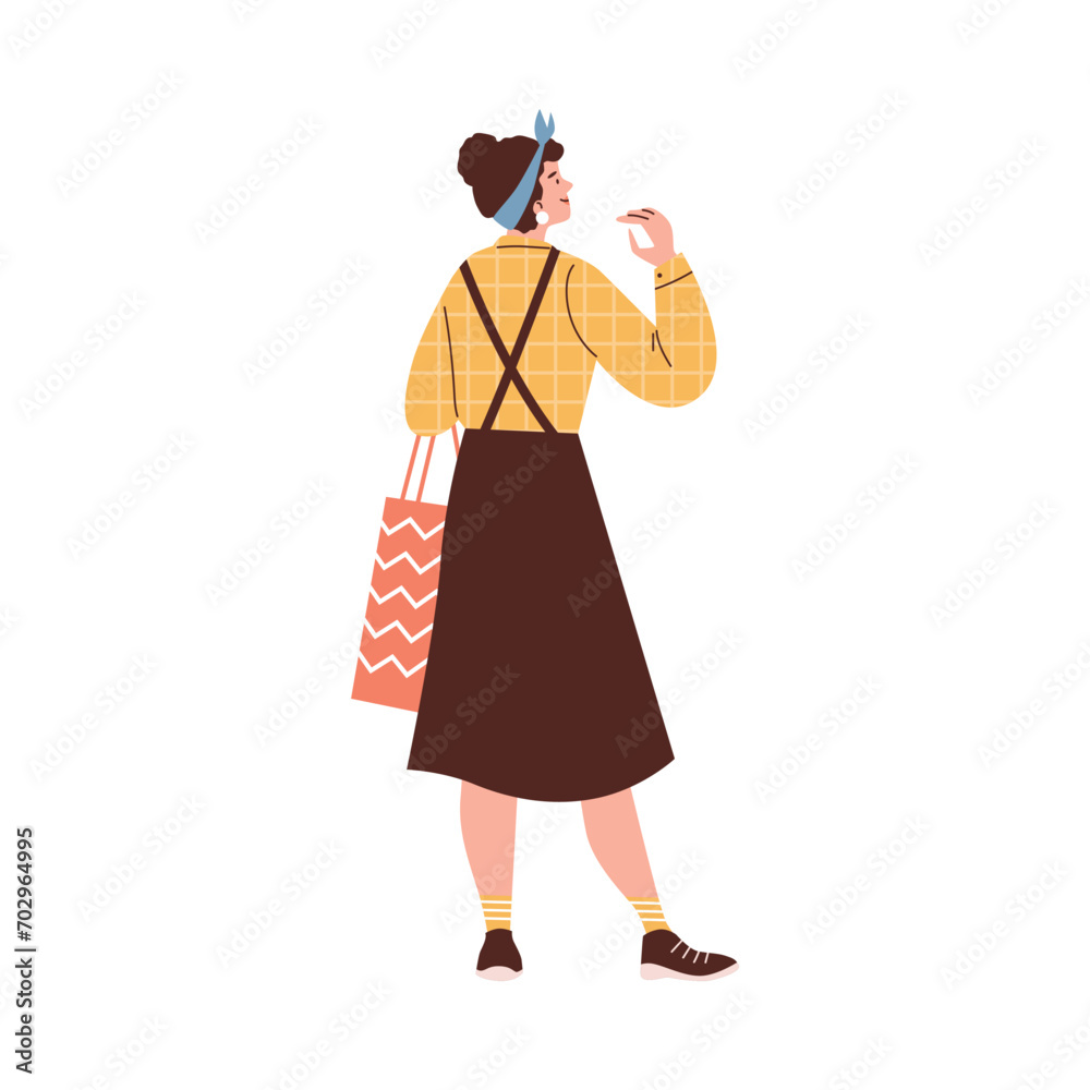 Girl wearing skirt, blouse and head scarf carrying paper bag.