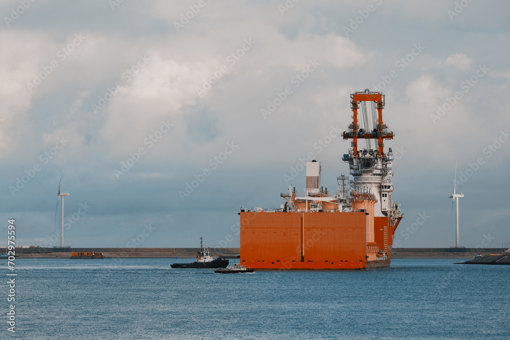 Semi-Submersible Installation Heavy Lift Vessel For The Offshore Wind Industry Entering The European Port  Under Assistance Of The Port Tug Boat