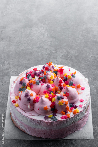 Pink Sponge cake decorated with small meringue on top on gray background photo