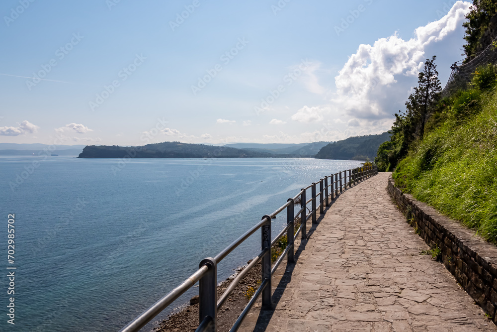 Obraz premium Scenic walking path between Fiesa and charming coastal town of Piran in Slovenian Istria, Slovenia, Europe. Rugged rocky cliffs gracefully perched above shimmering waters of the Adriatic Sea. Seascape