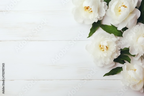 Flat lay of white peony flowers with copyspace on wooden background