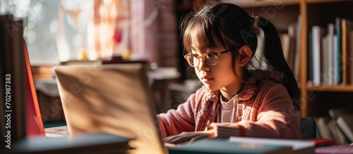 Asian child studying online at home with a laptop for homeschool education.
