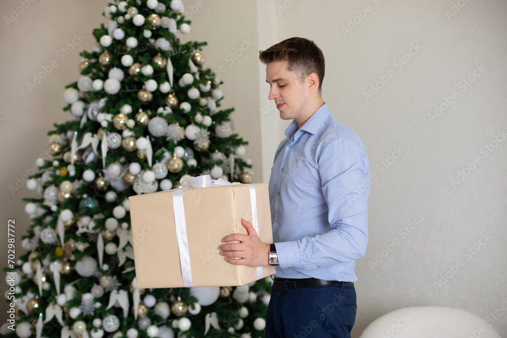 Young handsome man staying in living room and holding Christmas gift
Young handsome man staying in living room and holding Christmas gift