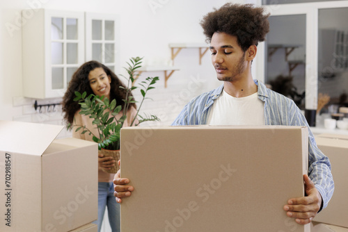 African American couple, man woman, collect clothes and plants in cardboard boxes for moving. happy young people relocating to new home. mortgage or rental of real estate. moving movers service