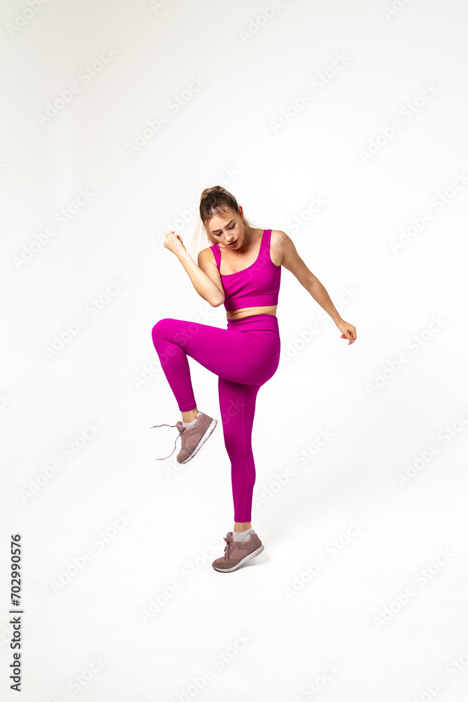 Woman in vibrant pink sports outfit with one bent leg and arm