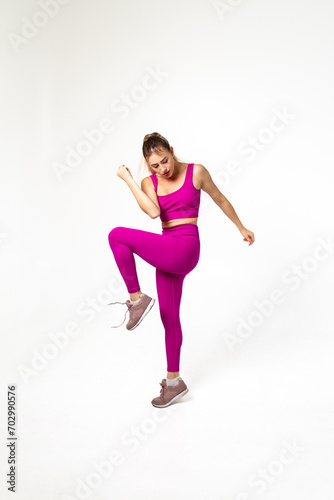 Fototapeta Naklejka Na Ścianę i Meble -  Woman in vibrant pink sports outfit with one bent leg and arm