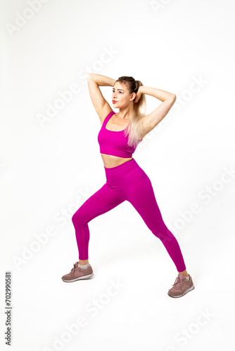 Woman in vibrant pink sports outfit with bent leg and hands behind head