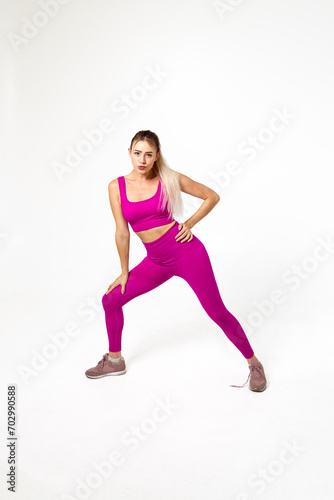 Woman in vibrant pink sports outfit with bent leg and hand leaning on it