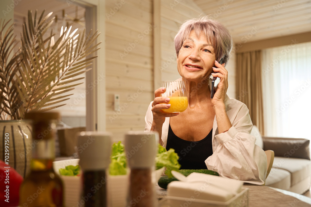 Elderly lady communicates on a mobile phone in her kitchen