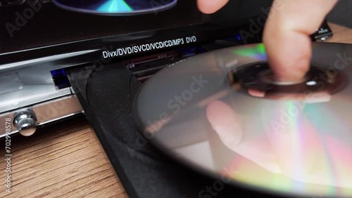 The compact disc is inserted into the DVD player. Male hand loads CD into a CD player tray close-up. Music, movies, or data recorded on a laser optical information storage medium. Loading Compact Disc