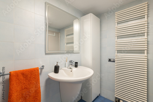 Mirror  sink and towel dryer in modern tiled bathroom