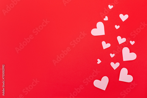 Pink paper hearts on a red background. Love concept. Valentine's Day. Top view. Space for text.