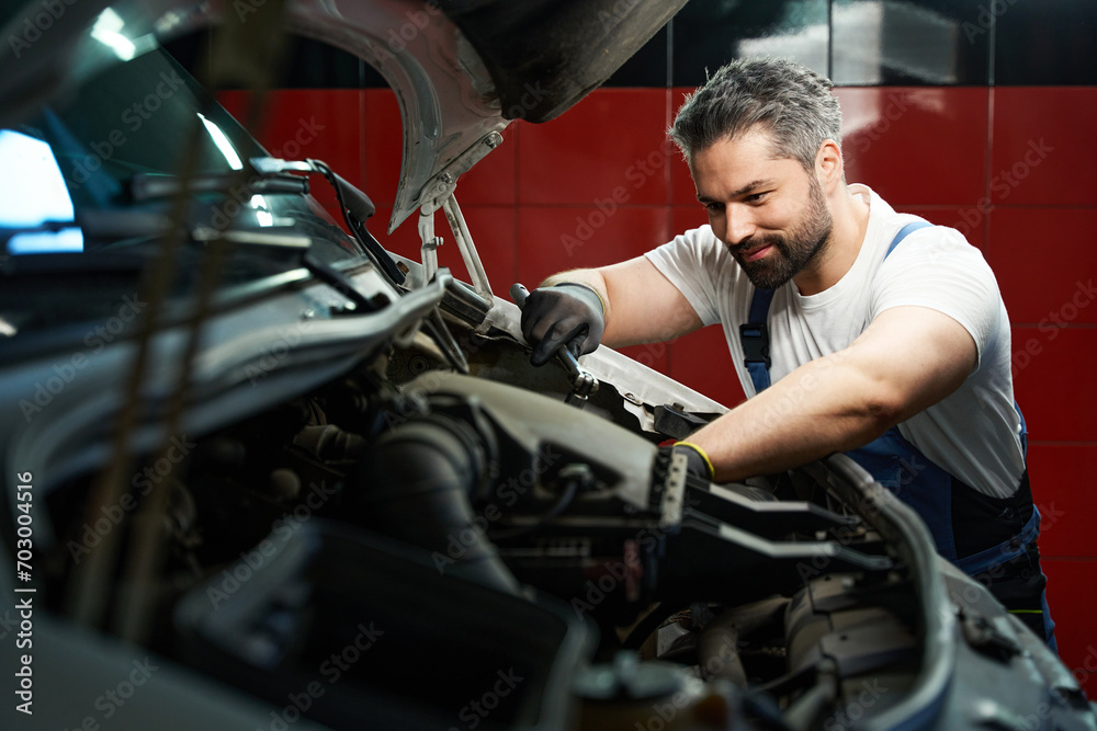Professional car service technician is fixing his customer automobile