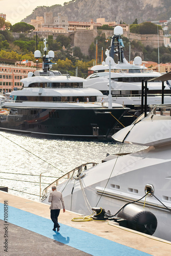 Few huge luxury yachts at the famous motorboat exhibition in the principality of Monaco, Monte Carlo, the most expensive boats for the richest people, mountain and residential complex on background © Vladimir Drozdin
