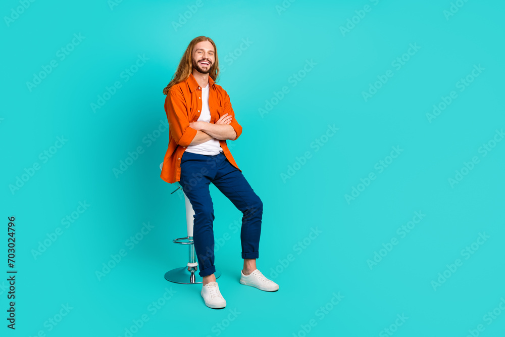 Full size photo of cool pleasant guy wear stylish outfit sit on stool in barbershop arms crossed isolated on turquoise color background Full size photo of cool pleasant guy wear stylish outfit sit on stool in barbershop arms crossed isolated on turquoise color background