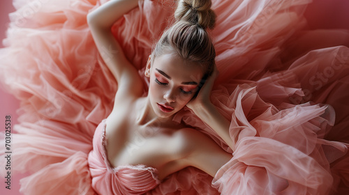 Beautiful ballet dancer in delicate, pink dress, resting after ballet performance. A Ballerina's Quiet Moment. photo