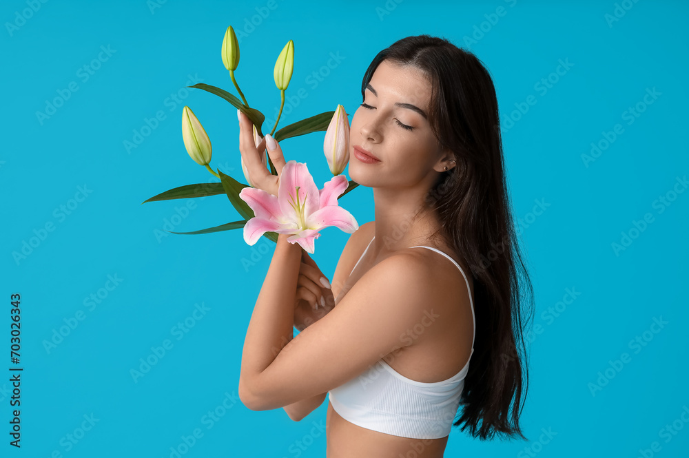 Young woman with lily flowers on blue background