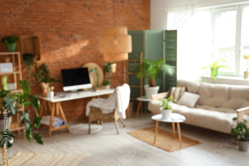 Blurred view of office with workplace  green plants and sofa
