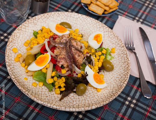 Traditional Spanish salad Xato, made from escalora, chopped salted cod, anchovies, olives, corn, onions, boiled eggs, red ..pepper and herbs, seasoned with sauce photo