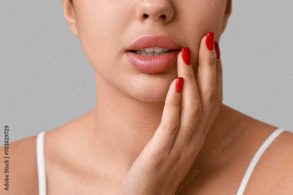 Young woman with beautiful lips and stylish manicure on grey background Young woman with beautiful lips and stylish manicure on grey background