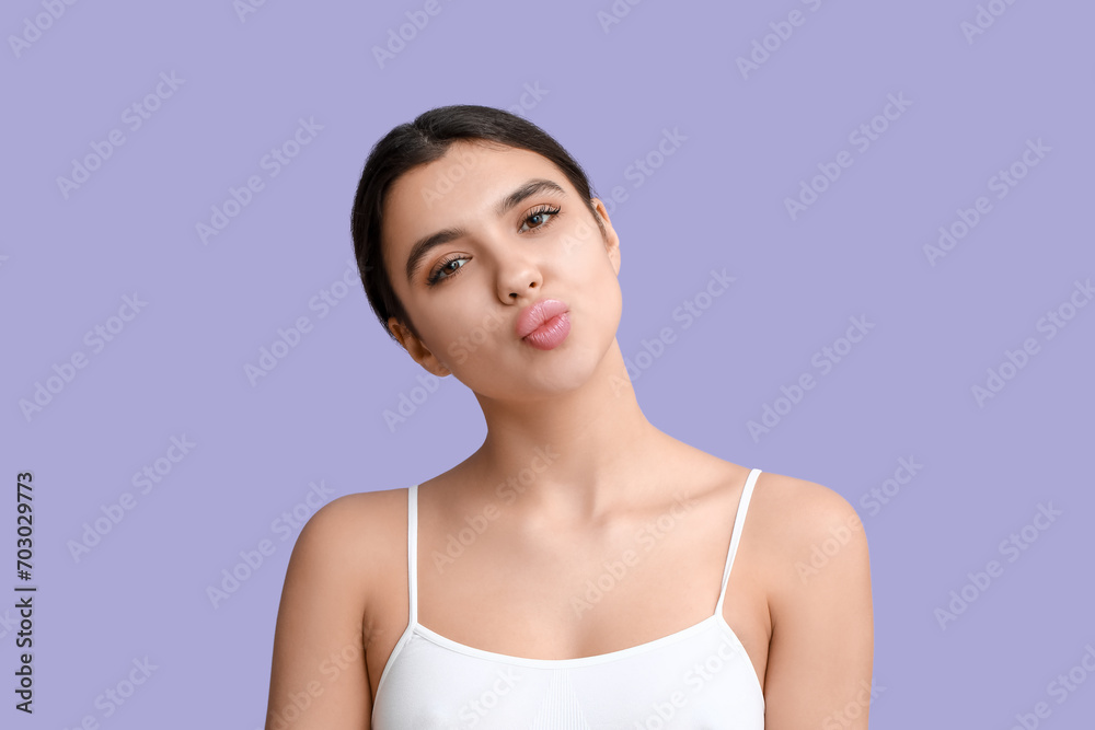 Beautiful young woman blowing kiss on lilac background