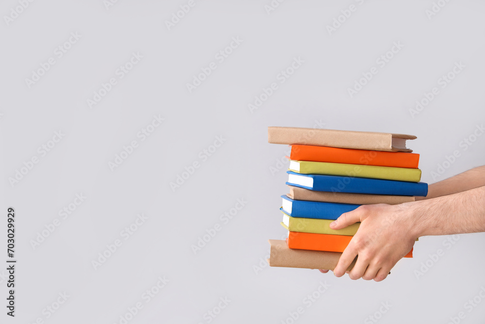 Fototapeta premium Hands holding stack of books on grey background